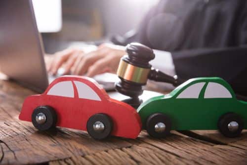 een rode en groene speelgoedauto botsen op elkaar op bureau van jurist