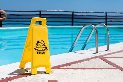 geel bordje dat waarschuwt voor gladde vloer aan de rand van zwembad