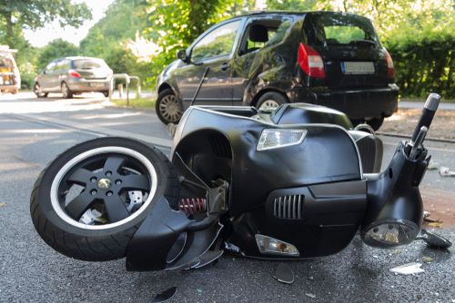 kapotte scooter ligt op de weg na aanrijding met auto