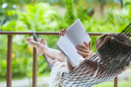 vrouw ligt in de hangmat een boek te lezen