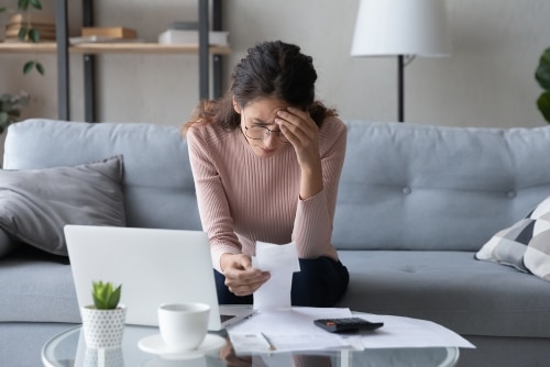 vrouw achter een laptop met een bonnetje in haar hand